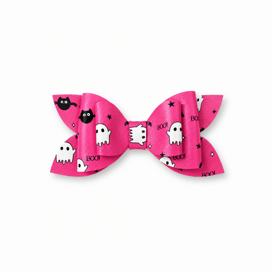 A pink hair bow with a Halloween pattern featuring white ghosts, black bats, black stars, and the word 'BOOM' in black text.