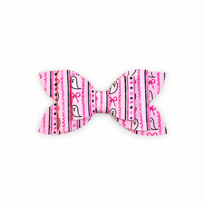 A faux leather hair bow featuring a pink and white pattern with cartoon ghosts, black stripes, and small pink bows, shown on a plain white background.